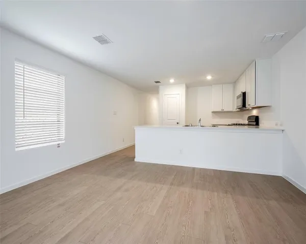 a view of a kitchen with kitchen island a sink wooden floor and counter top space