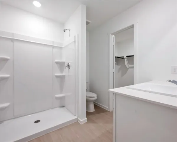 a bathroom with a granite countertop sink a toilet and shower