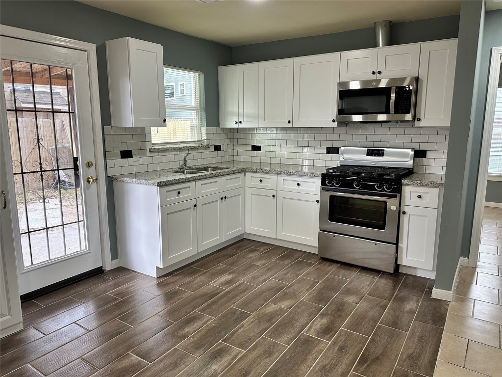 6911 Bauman Road Houston, TX 77022 - Photo 5 of 17 a kitchen with stainless steel appliances granite countertop a stove a sink and a microwave