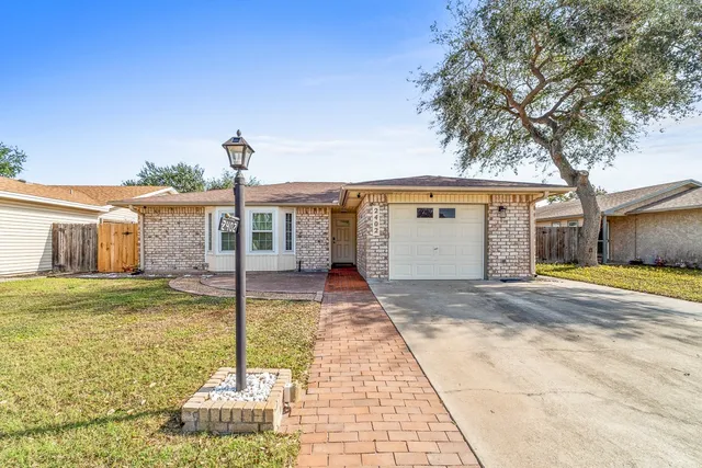 a front view of a house with a garden and trees