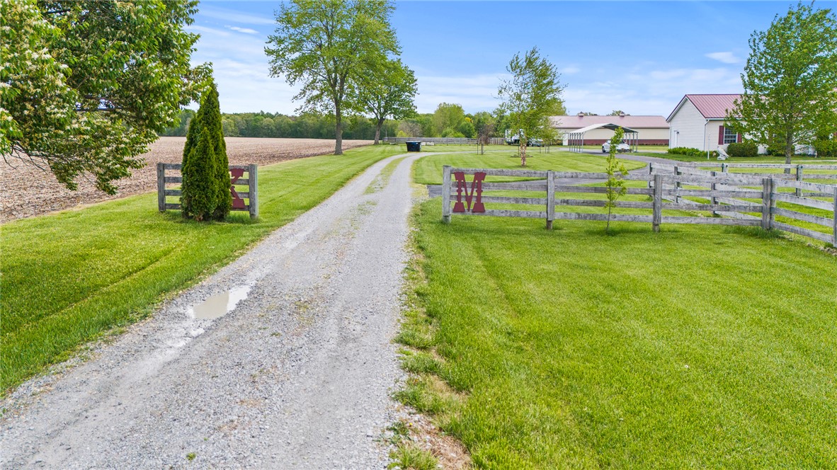 4222 Ramsey Road Springfield, OH 45502 - Photo 9 of 79 A long gravel driveway leads to a secluded estate, bordered by a rustic wooden fence.