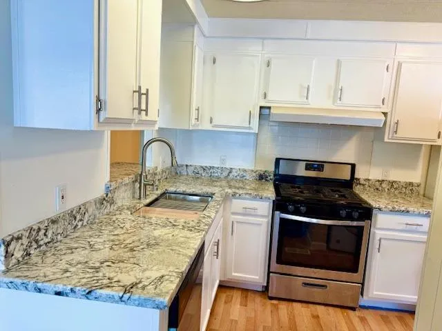 a kitchen with granite countertop a stove sink and cabinets