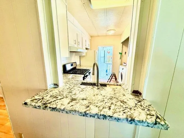 a bed sitting in a kitchen next to a window