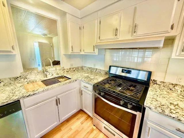a kitchen with granite countertop a stove sink and cabinets