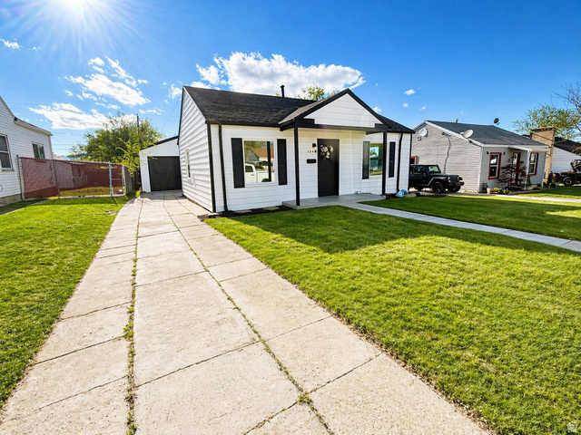 Bungalow-style home featuring a front lawn, a garage, an outdoor structure, and concrete driveway