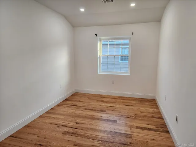 a view of an empty room with wooden floor and closet