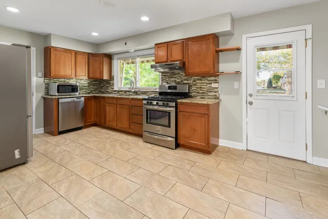 a kitchen with stainless steel appliances granite countertop a stove a sink and a refrigerator