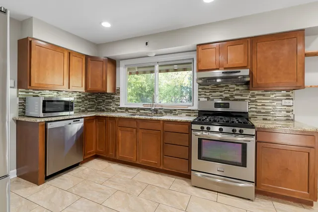 a kitchen with granite countertop wooden cabinets stainless steel appliances and a window