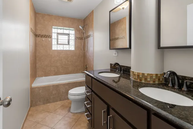 a bathroom with a granite countertop sink a toilet a mirror a bathtub and shower