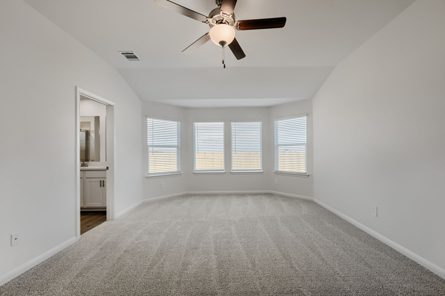 146 Diablo Rim Terrace Dripping Springs, TX 78620 - Photo 17 of 32 A spacious primary bedroom featuring a bay window with natural light and a ceiling fan for comfort.