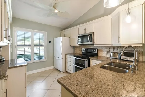 a kitchen with granite countertop a stove sink and refrigerator