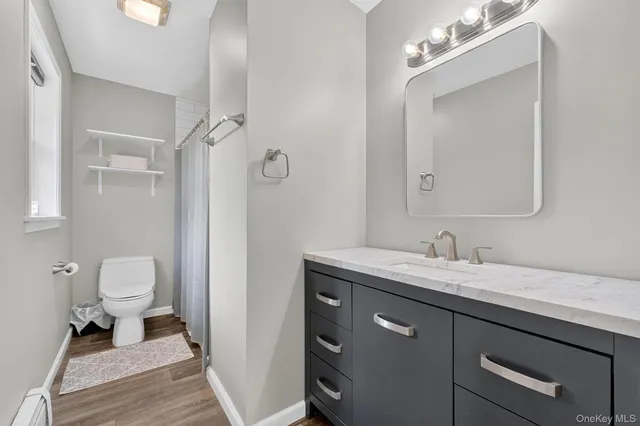 a bathroom with a granite countertop sink a toilet and a mirror