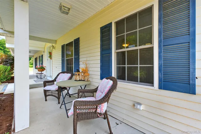 a balcony with table and chairs and potted plants