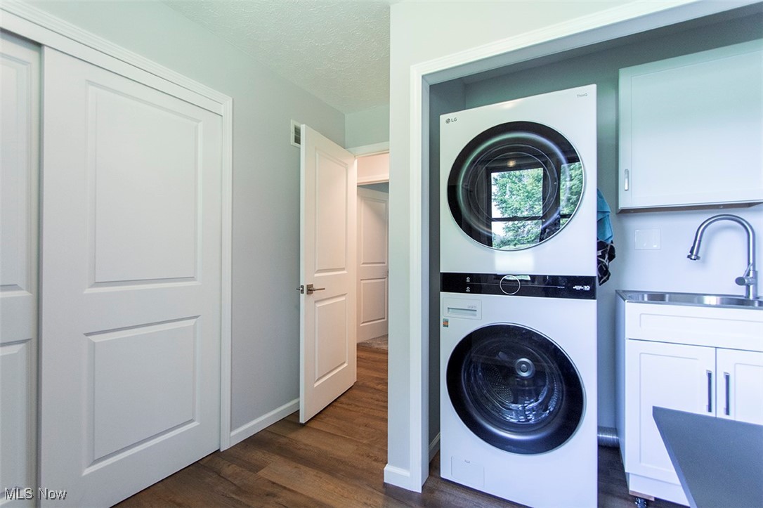 5859 Buffham Road Seville, OH 44273 - Photo 22 of 34 Laundry area featuring stacked washer / dryer, cabinet space, dark wood finished floors, and a textured ceiling