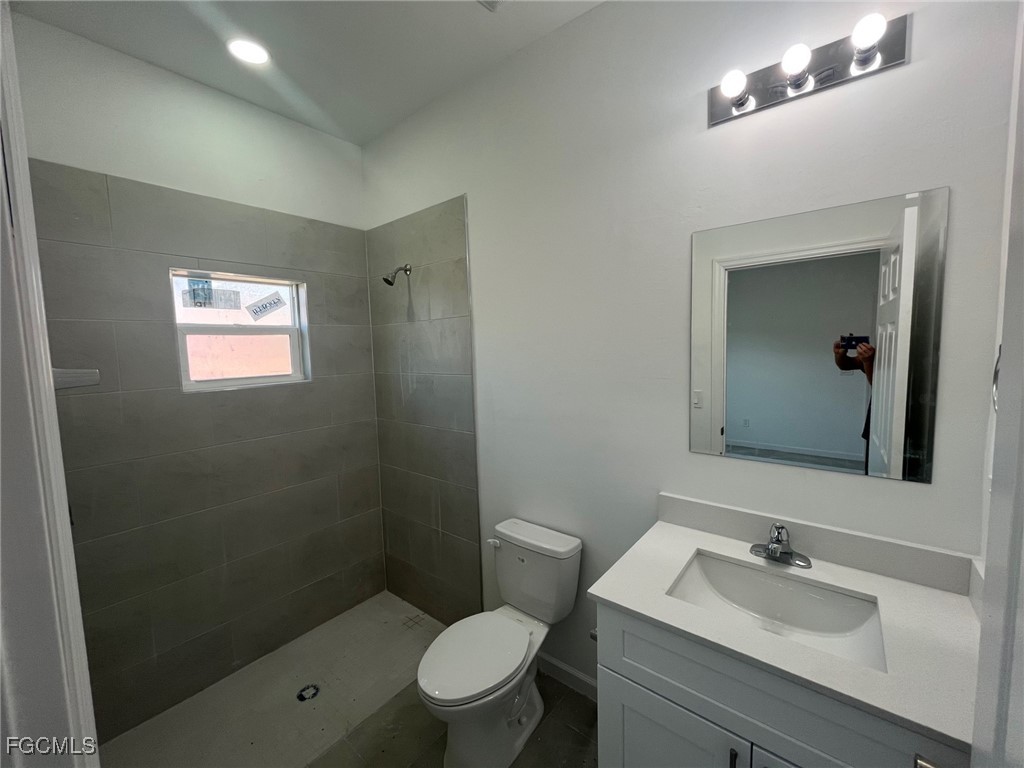 3307 50th Street West Lehigh Acres, FL 33971 - Photo 10 of 15 a bathroom with a sink a toilet a mirror and shower