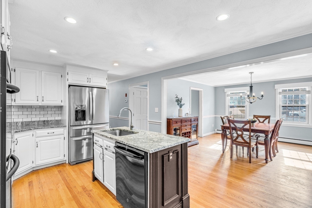 3 Erin Lane Norfolk, MA 02056 - Photo 10 of 37 a kitchen with stainless steel appliances granite countertop a stove top oven a sink dishwasher a dining table and chairs with wooden floor