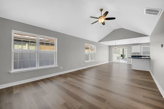 a view of an empty room with window and wooden floor