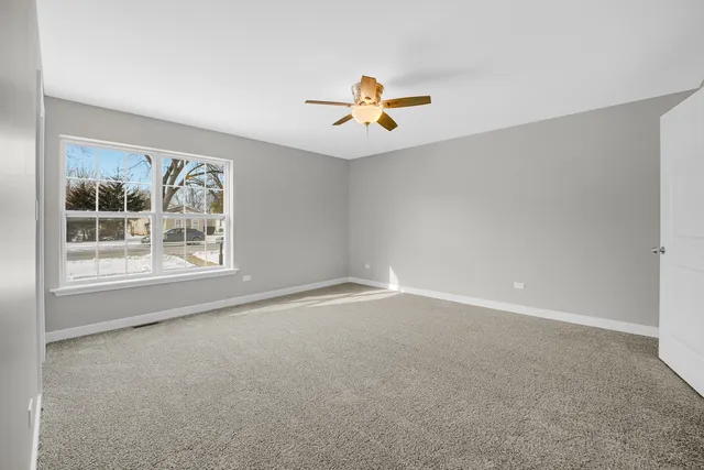 an empty room with windows and fan