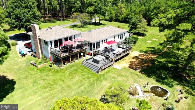 an aerial view of a house with swimming pool lawn chairs and large trees