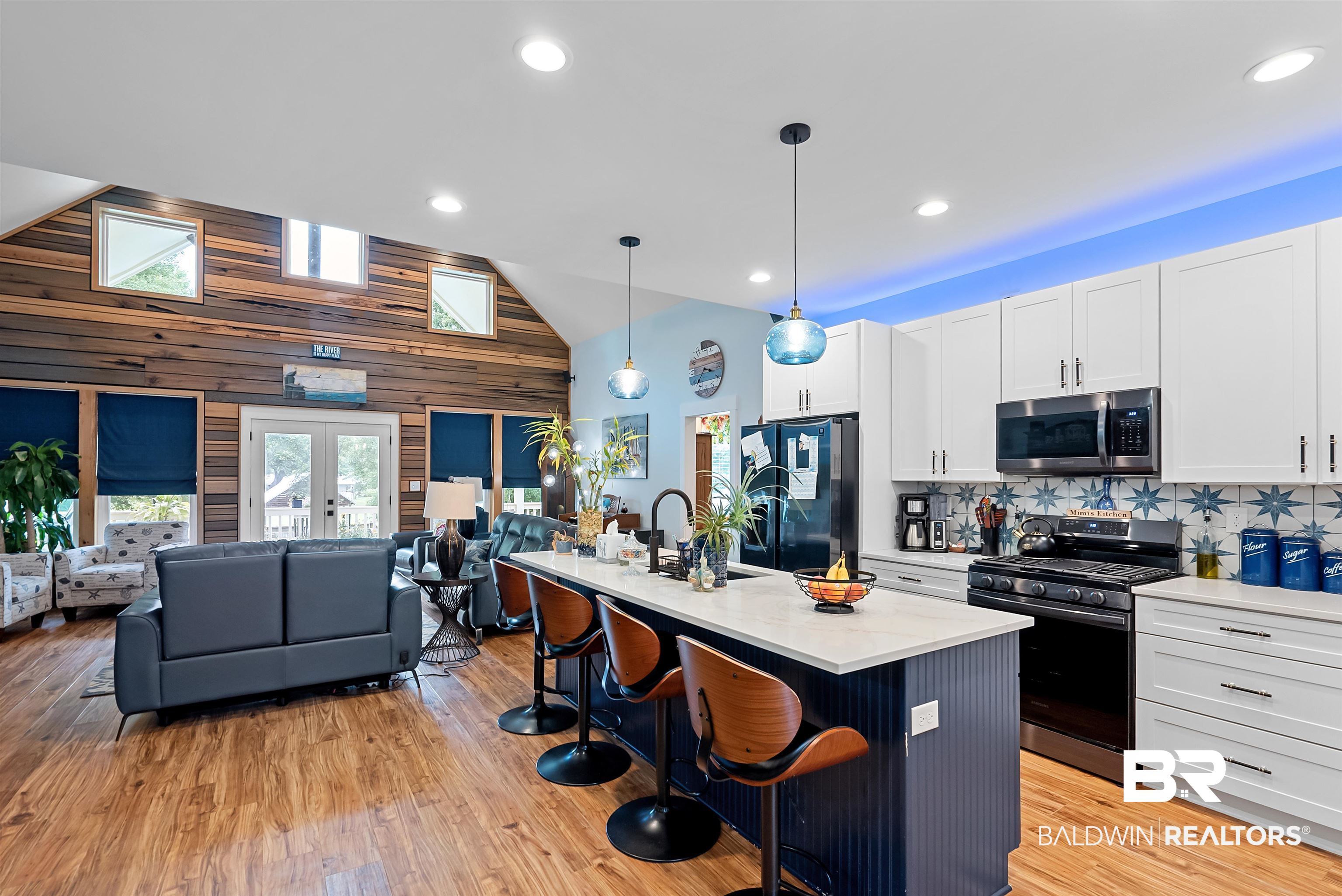 7266 Franklin Road Foley, AL 36535 - Photo 11 of 64 Open-concept kitchen and living area featuring wood-finish flooring, a vaulted ceiling, and a kitchen island with seating
