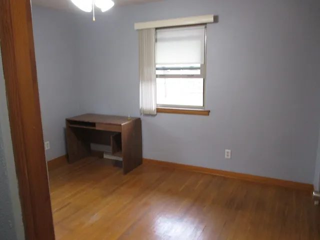an empty room with a window and wooden floor