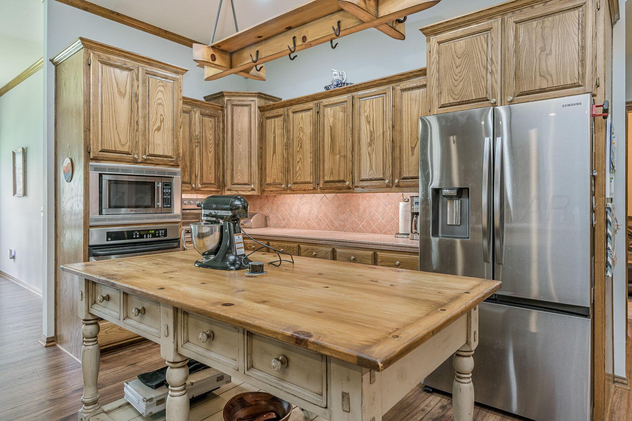 7 Pebble Beach Court Amarillo, TX 79124 - Photo 6 of 67 a kitchen with kitchen island a counter top space appliances and a refrigerator