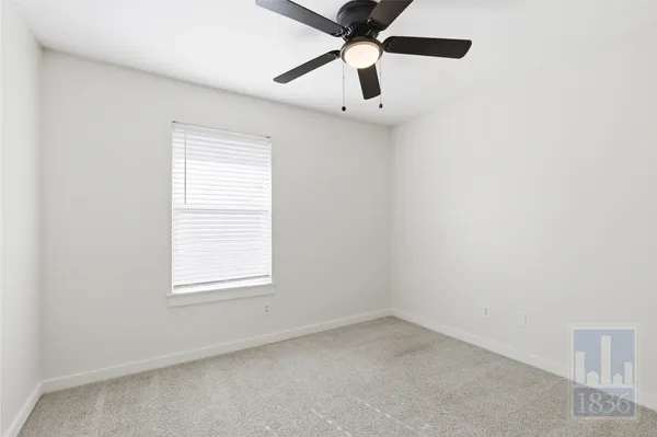 an empty room with a window and a fan