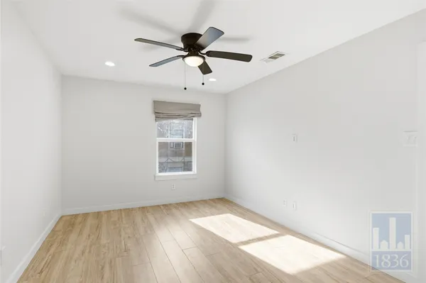 a view of empty room with wooden floor and fan