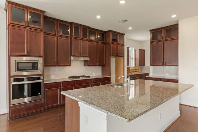 a kitchen with stainless steel appliances granite countertop a sink a microwave and wooden cabinets