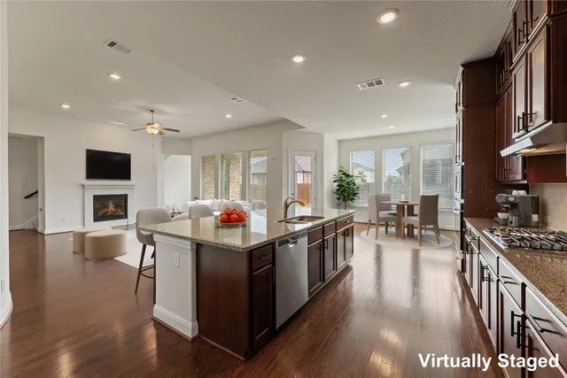 a living room with stainless steel appliances kitchen island granite countertop a stove and a wooden floors