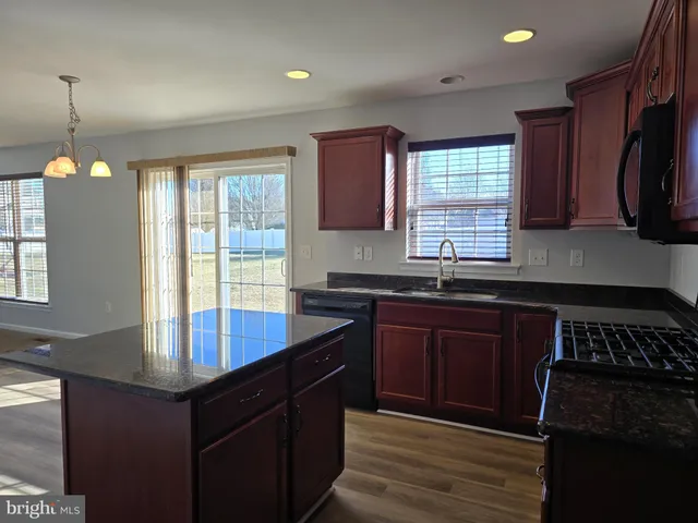 a kitchen with kitchen island granite countertop a sink stove and cabinets