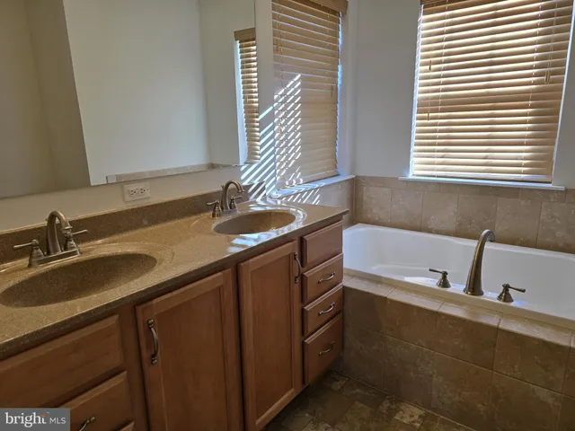 a bathroom with a granite countertop sink and a bathtub