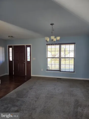 an empty room with chandelier fan and windows
