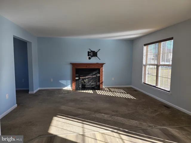 a view of an empty room with a fireplace and a window