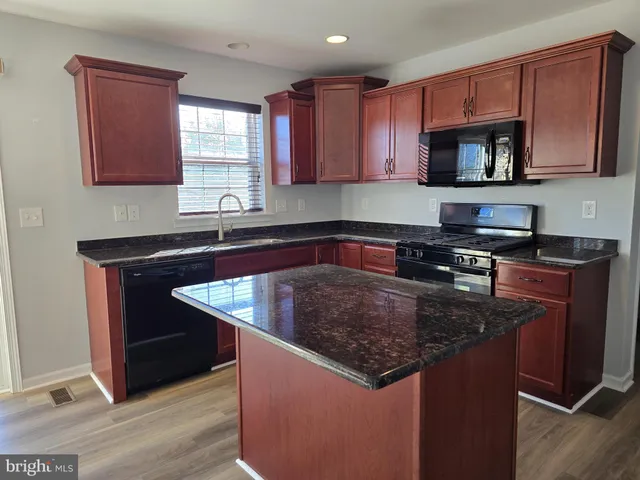 a kitchen with kitchen island granite countertop a sink stove and microwave