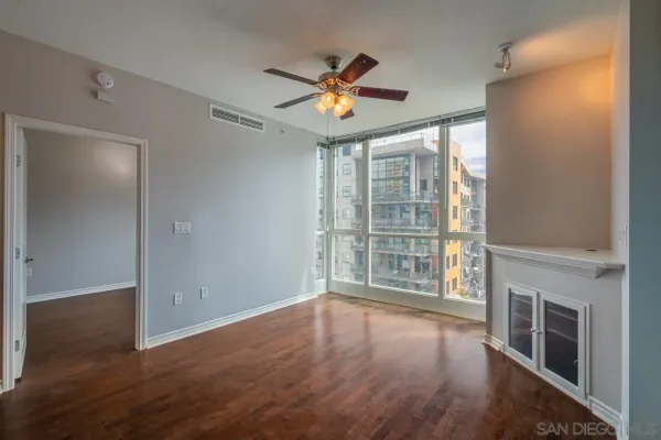 a view of an empty room with wooden floor and a window