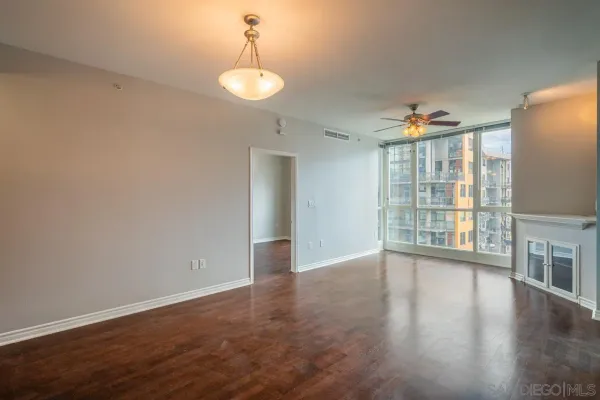 a view of an empty room with wooden floor and a window