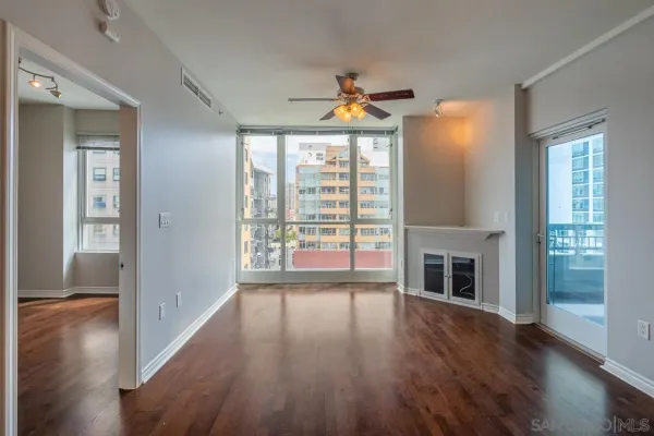 a view of empty room with wooden floor and fan