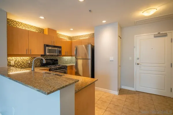 a kitchen with stainless steel appliances granite countertop a refrigerator a stove and a sink