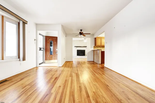 a view of a kitchen from the hallway with a fireplace and wooden floor