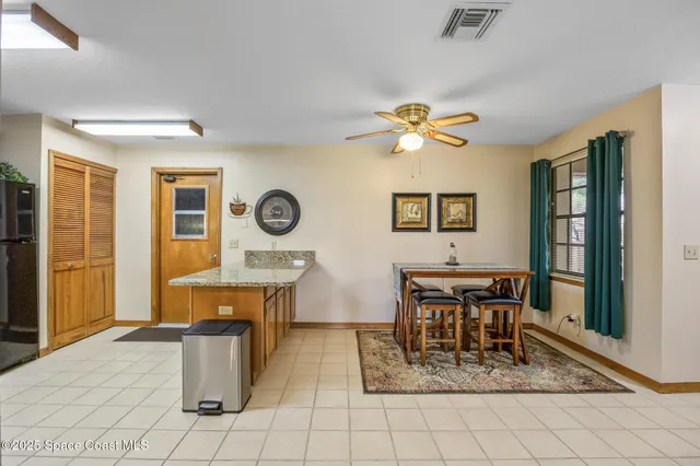 a dining room with chandelier fan and wooden furniture