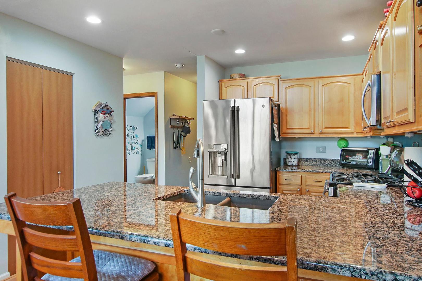 521 Willow Way Lindenhurst, IL 60046 - Photo 3 of 24 a kitchen with stainless steel appliances granite countertop a refrigerator a stove and white cabinets with wooden floors