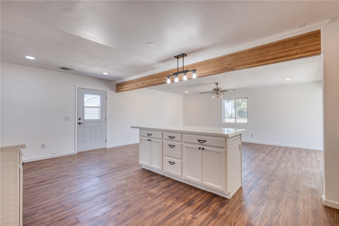 2053 Regents Road Mohave Valley, AZ 86440 - Photo 12 of 65 The open concept living area features laminate wood flooring, a white kitchen island with a quartz countertop, and a decorative exposed wood beam
