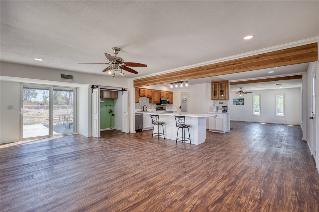 2053 Regents Road Mohave Valley, AZ 86440 - Photo 13 of 65 The spacious open-concept living area features wood-look flooring, exposed ceiling beams, and a ceiling fan