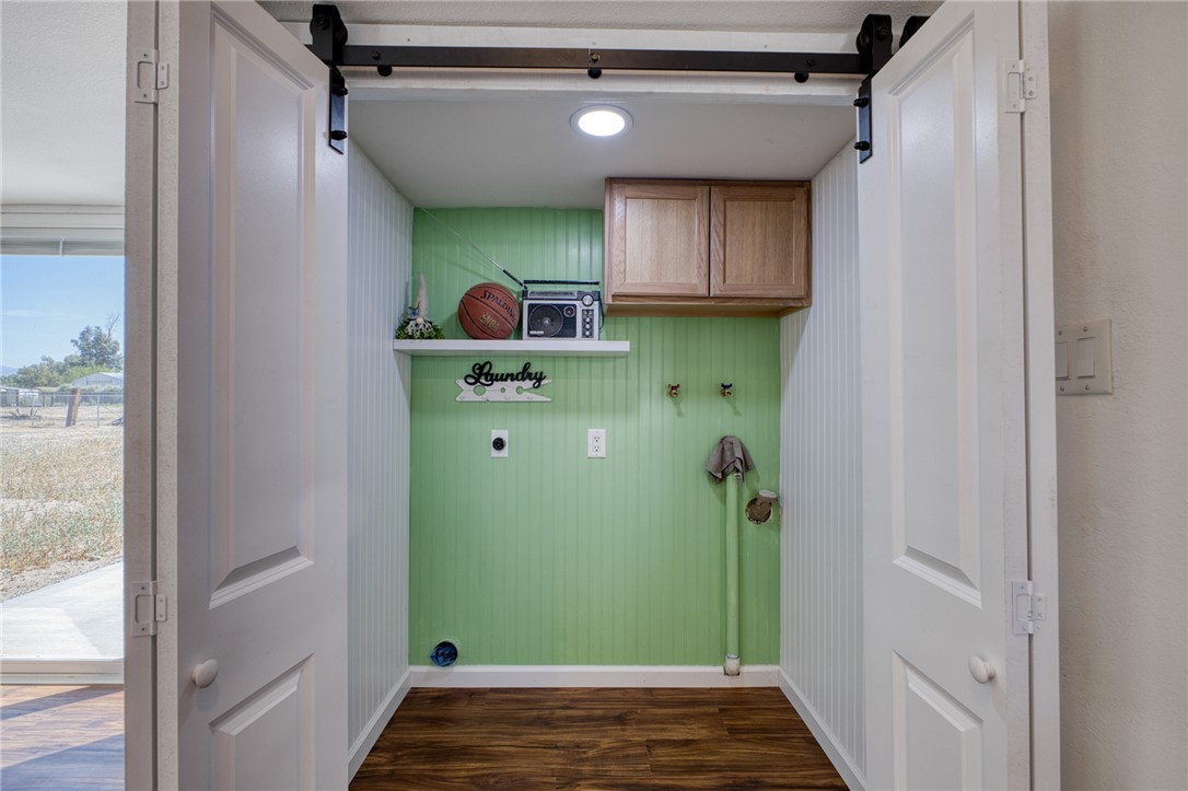2053 Regents Road Mohave Valley, AZ 86440 - Photo 14 of 65 Dedicated laundry area featuring a bright green accent wall, wood flooring, and a ceiling-mounted light fixture