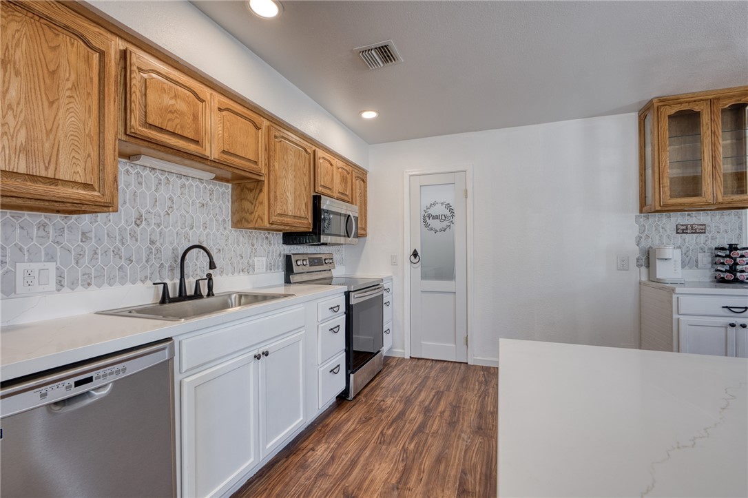 2053 Regents Road Mohave Valley, AZ 86440 - Photo 15 of 65 The kitchen features white shaker style lower cabinetry, natural wood upper cabinetry, a white countertop, and a stainless steel dishwasher