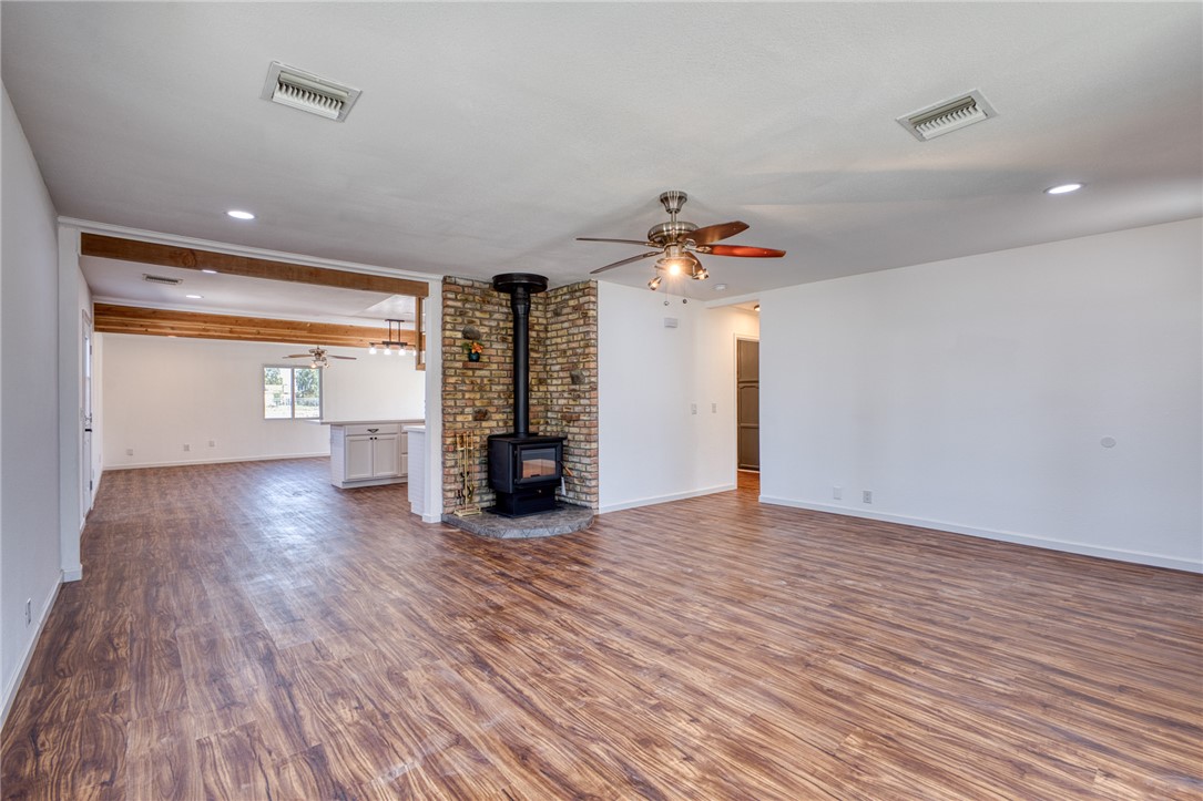 2053 Regents Road Mohave Valley, AZ 86440 - Photo 18 of 65 Spacious living area featuring wood-look flooring, a brick-surround wood-burning stove, and a ceiling fan