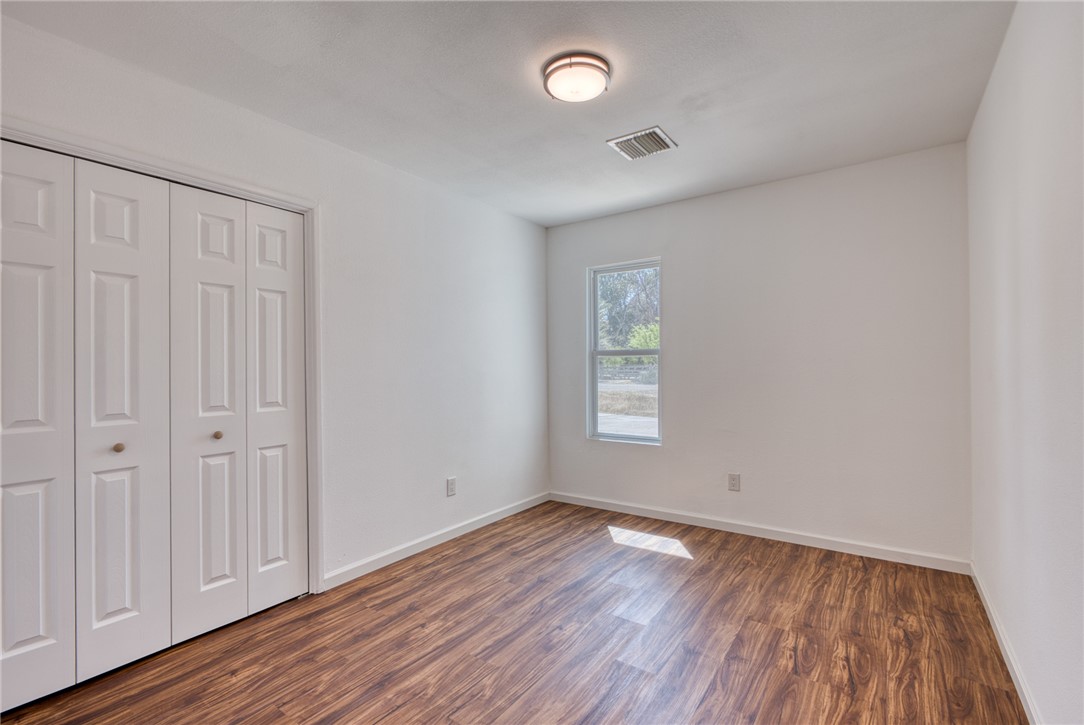 2053 Regents Road Mohave Valley, AZ 86440 - Photo 19 of 65 This room features wood-look flooring, white walls, and a window with a view of exterior trees