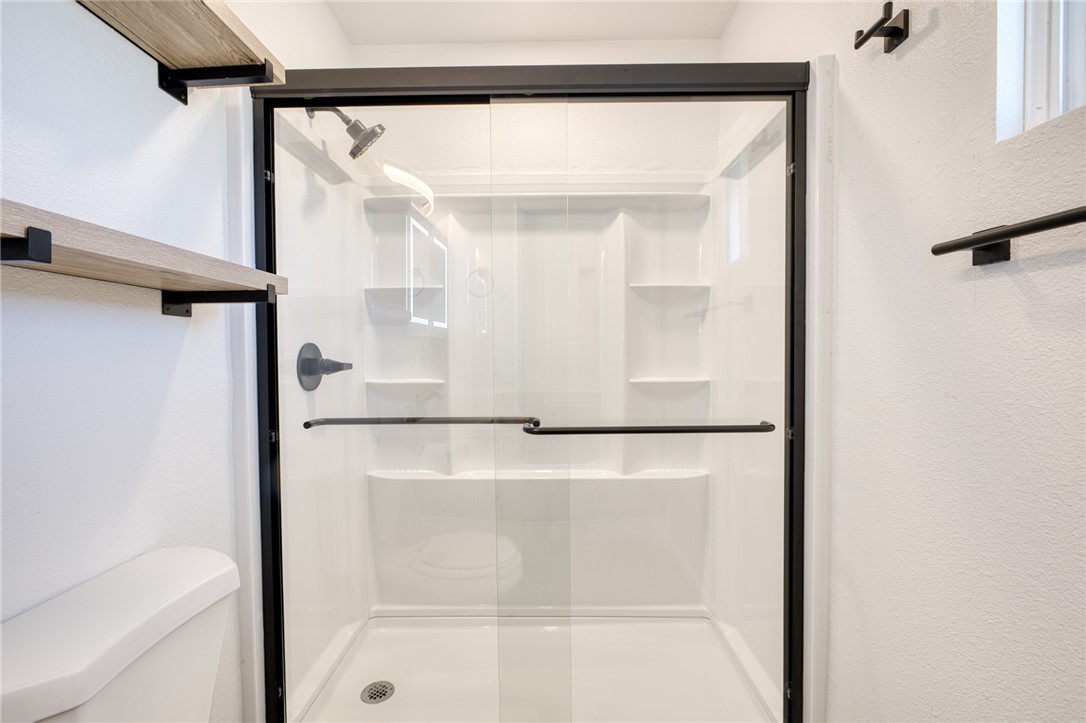 2053 Regents Road Mohave Valley, AZ 86440 - Photo 31 of 65 The bathroom features a shower enclosure with a clear glass door and black framing, a shower head, and a toilet