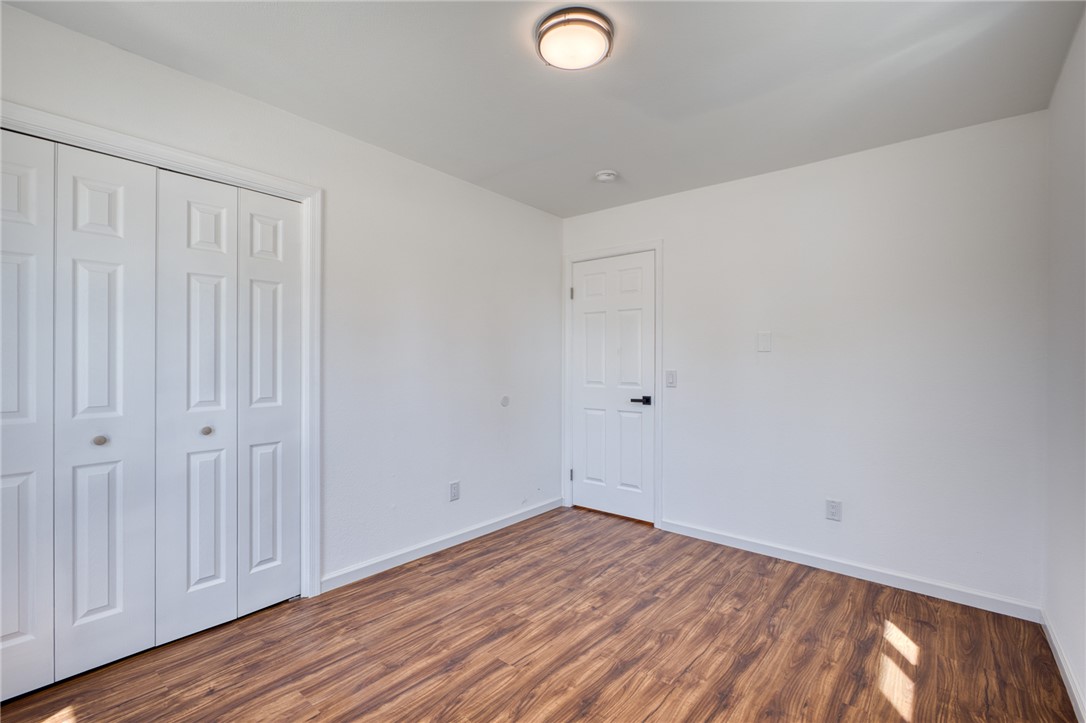 2053 Regents Road Mohave Valley, AZ 86440 - Photo 34 of 65 The room features bright white walls, wood-style flooring, a white paneled door, and a flush mount ceiling light